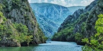 "Kayaking in the serene waters of Matka Canyon with towering cliffs in the background."