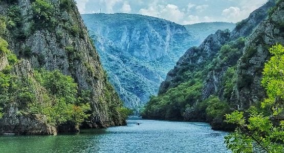 "Kayaking in the serene waters of Matka Canyon with towering cliffs in the background."