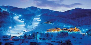 "Panoramic view of Mavrovo National Park showcasing Lake Mavrovo's tranquil waters surrounded by lush green forests and towering mountains in the background."