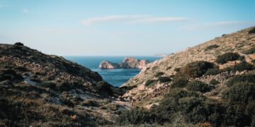 Agios Nikolaos, Greece — Explore the stunning coastal landscape of Agios Stefanos in Greece, featuring rugged mountains and serene sea views.