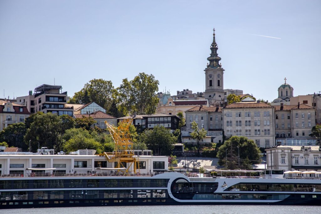 Belgrade, Serbia — A picturesque view of Belgrade's waterfront featuring St. Michael's Cathedral and urban architecture under clear summer skies.