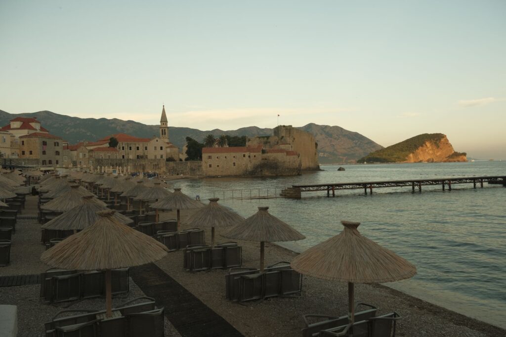 Budva, Montenegro — Scenic view of Budva Old Town at sunset with beach umbrellas in Montenegro.