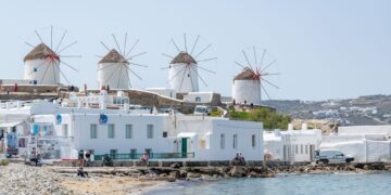Cyclades Islands, Greece — Picturesque view of Mykonos windmills with white buildings by the sea, perfect summer scene.