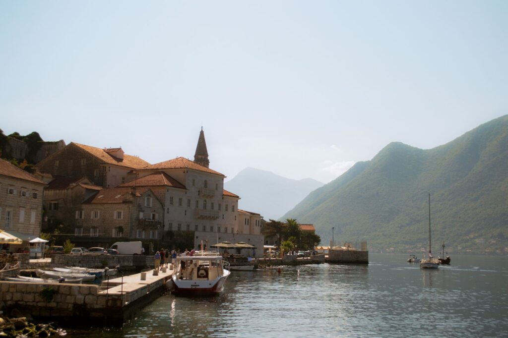 Kotor, Montenegro — Charming view of Perast harbor with boats and historic buildings against mountainous backdrop.