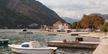 Kotor, Montenegro — Tranquil harbor scene with boats docked by the waterfront, surrounded by picturesque mountains.