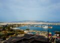 Loutraki, Greece — A picturesque marina view with yachts, cityscape, and distant mountains under a clear sky.