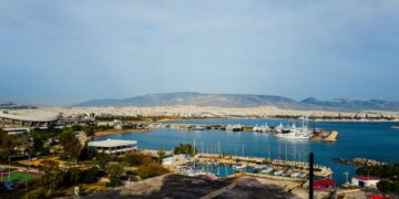 Loutraki, Greece — A picturesque marina view with yachts, cityscape, and distant mountains under a clear sky.