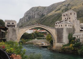 Mostar, Bosnia and Herzegovina — Scenic view of the historic Stari Most Bridge over the Neretva River in Mostar, surrounded by hills and buildings.