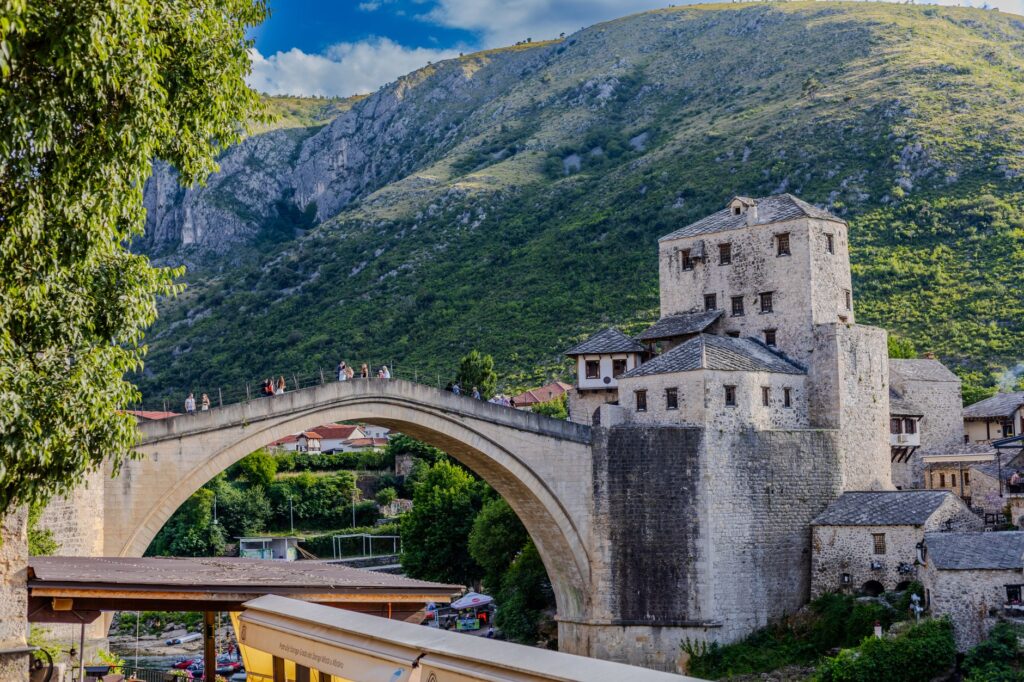 Mostar, Bosnia and Herzegovina — Scenic view of the historic arch bridge in Mostar with lush hills and the Neretva River.