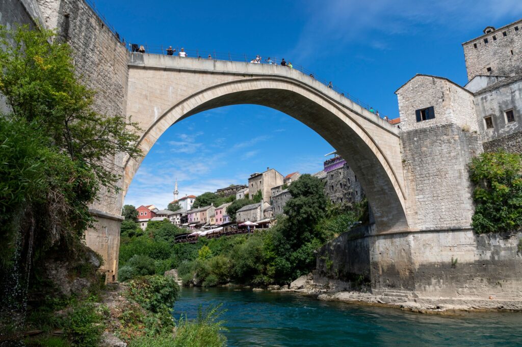 Mostar, Bosnia and Herzegovina — The historic Stari Most bridge spans the Neretva River in Mostar, Bosnia, under a bright blue sky.