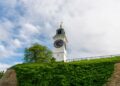 Novi Sad, Serbia — The iconic clock tower of Petrovaradin Fortress against a lush green backdrop.