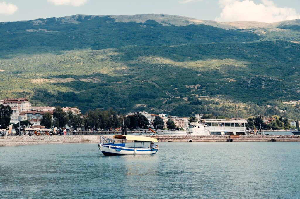 Ohrid, North Macedonia — Peaceful scene of a boat on Lake Ohrid with a mountainous backdrop in North Macedonia.