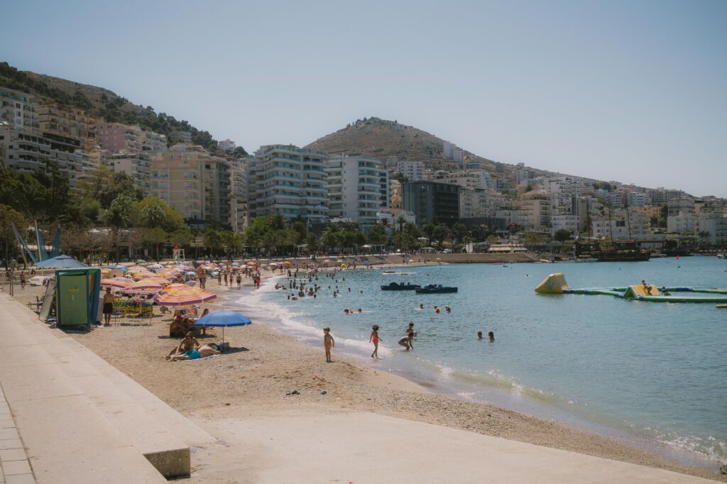 Saranda, Albania — A vibrant day at the bustling beach in Sarandë, Albania, with people enjoying the sun and sea.