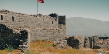 Shkoder, Albania — Historic Shkodra Castle ruins with Albanian flag, overlooking mountains.