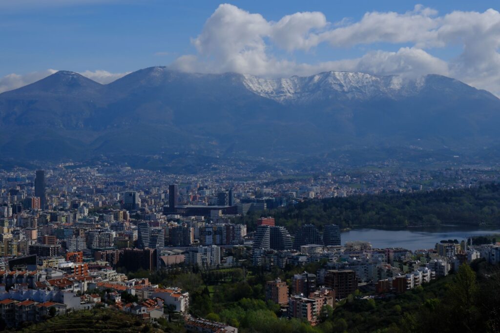 Tirana, Albania — A stunning cityscape view of Tirana with Dajti Mountain in the background, under a clear sky.