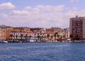 Trogir, Croatia — A beautiful cityscape featuring waterfront buildings and palm trees under a clear summer sky.