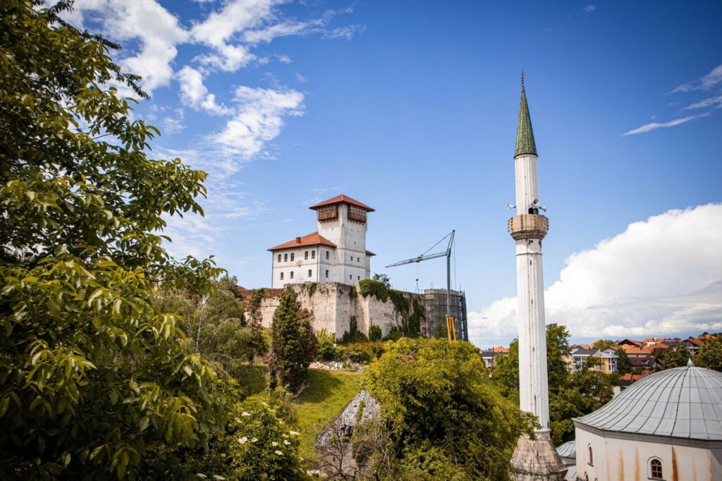 Visoko, Bosnia and Herzegovina — A stunning view of Gradačac Castle and minaret surrounded by lush greenery under a bright blue sky.
