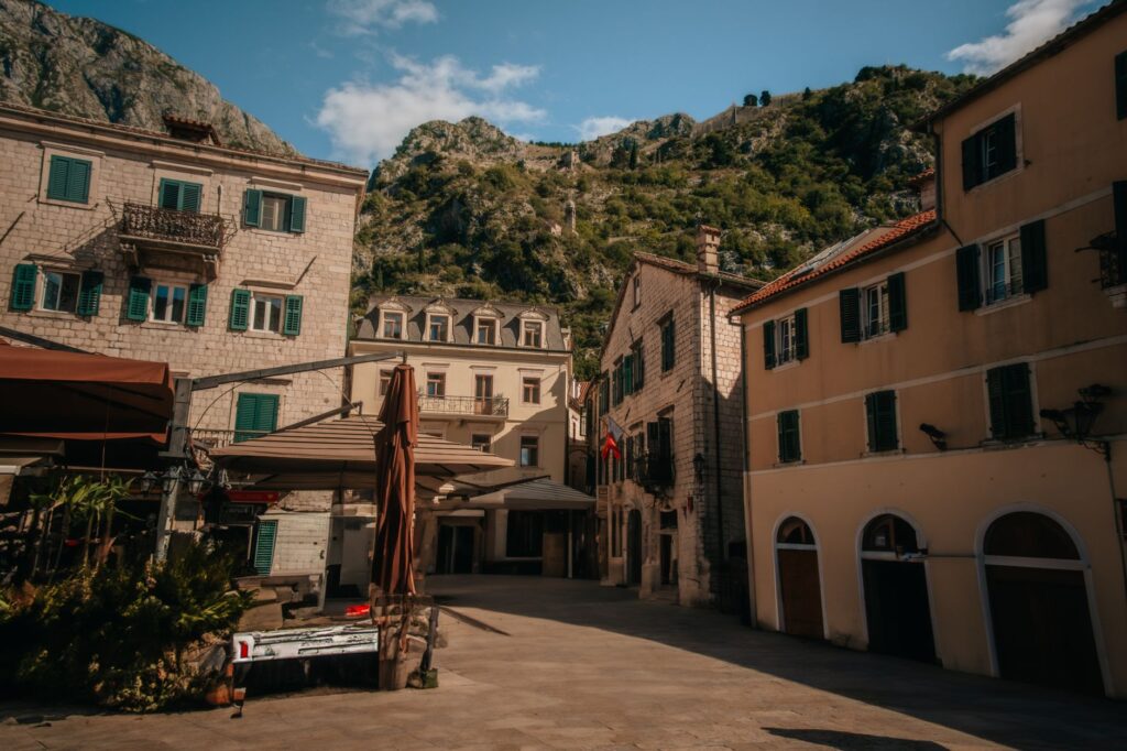 Kotor, Montenegro — Explore a picturesque square in Kotor's Old Town, framed by mountains and historic buildings.