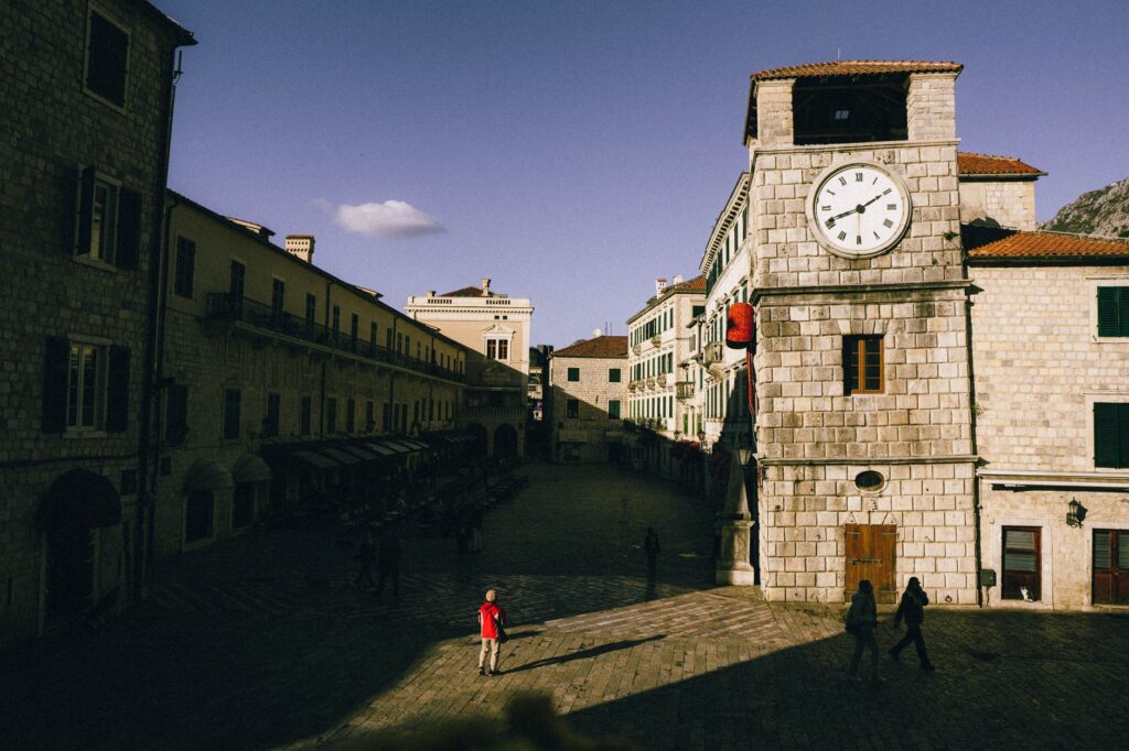 Kotor, Montenegro — Sunlit clock tower and medieval architecture at Kotor's Old Town square.