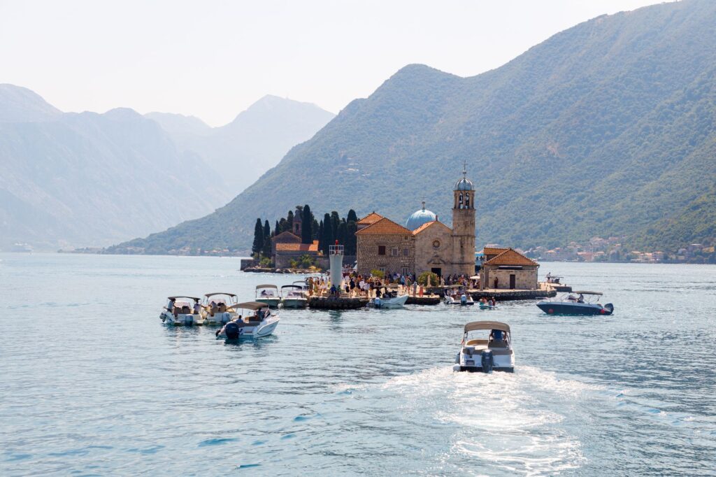 Kotor, Montenegro — Scenic view of boats heading towards Our Lady of the Rocks island in Montenegro's Bay of Kotor.