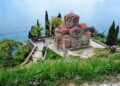 Ohrid, North Macedonia — Aerial view of Saint John Church at Kaneo with Lake Ohrid in the background, surrounded by greenery.