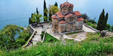 Ohrid, North Macedonia — Aerial view of Saint John Church at Kaneo with Lake Ohrid in the background, surrounded by greenery.