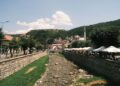 Prizren, Kosovo — Panoramic view of Prizren's charming riverside cafes and historic architecture on a sunny day.