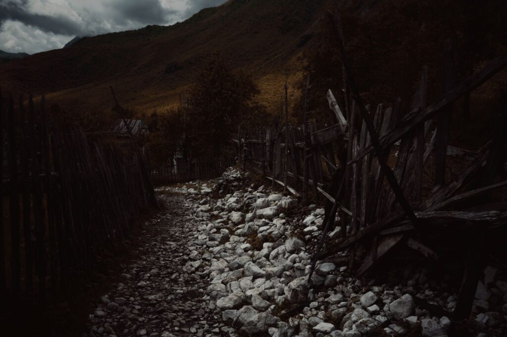 Theth, Albania — A moody rocky path through a rustic fence in Theth, Albania.