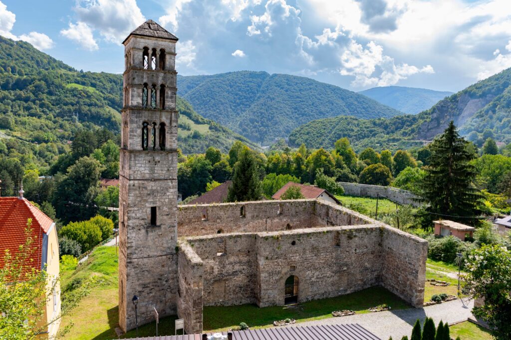 Jajce, Bosnia and Herzegovina — Explore the historic church ruins in Jajce, set against lush green landscapes and rolling hills.