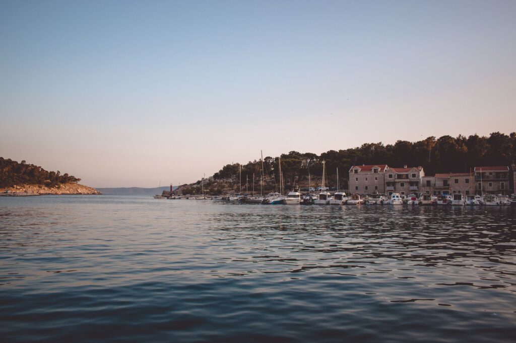 Makarska, Croatia — Beautiful harbor scene in Makarska, Croatia under a clear blue sky at sunset with boats docked.