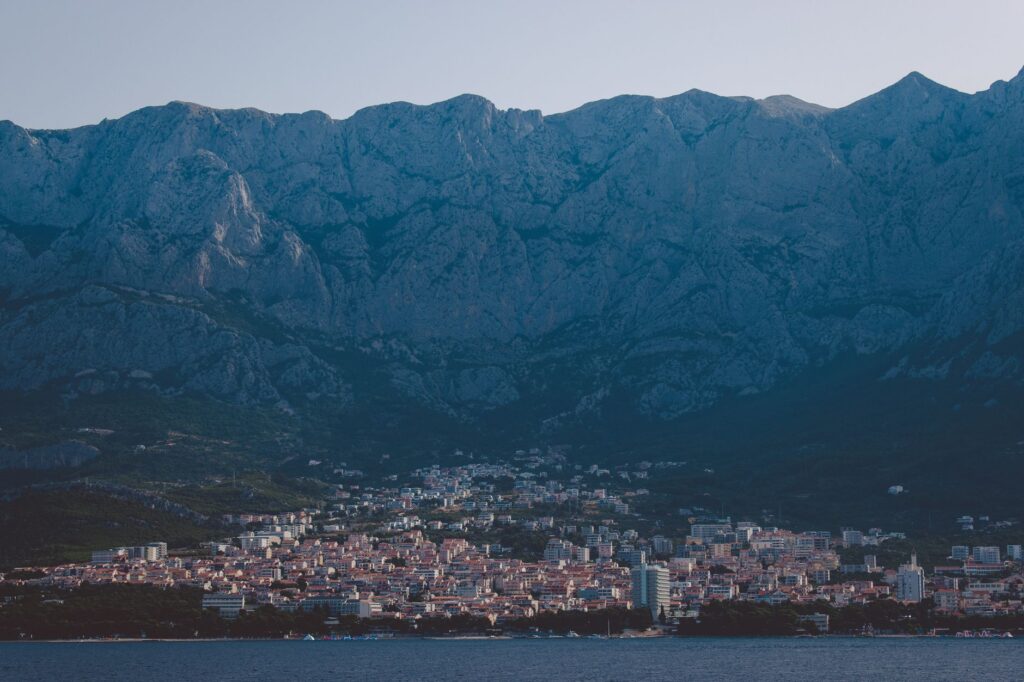 Makarska, Croatia — A breathtaking view of Makarska city nestled against a majestic mountain range by the sea.