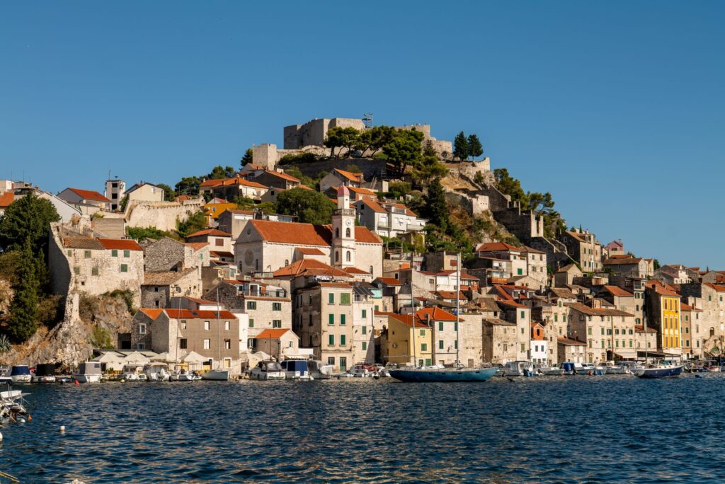 Šibenik, Croatia — Charming view of Šibenik's historic waterfront and medieval fortress under a clear sky.