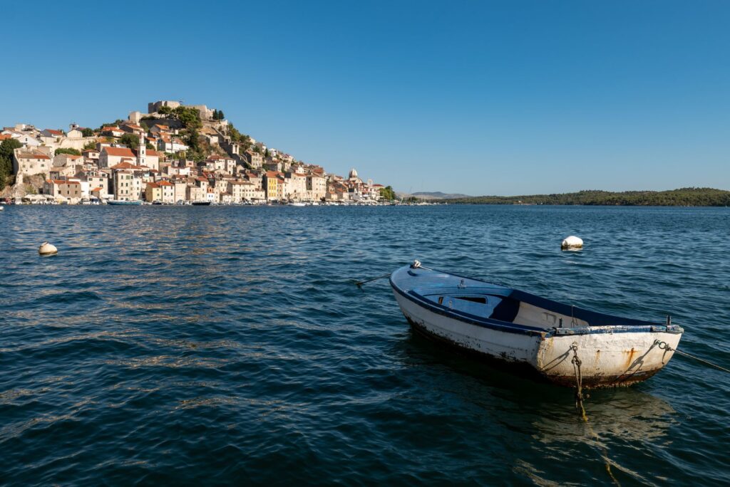 Šibenik, Croatia — Peaceful view of an empty boat floating in Šibenik's harbor under clear blue skies.