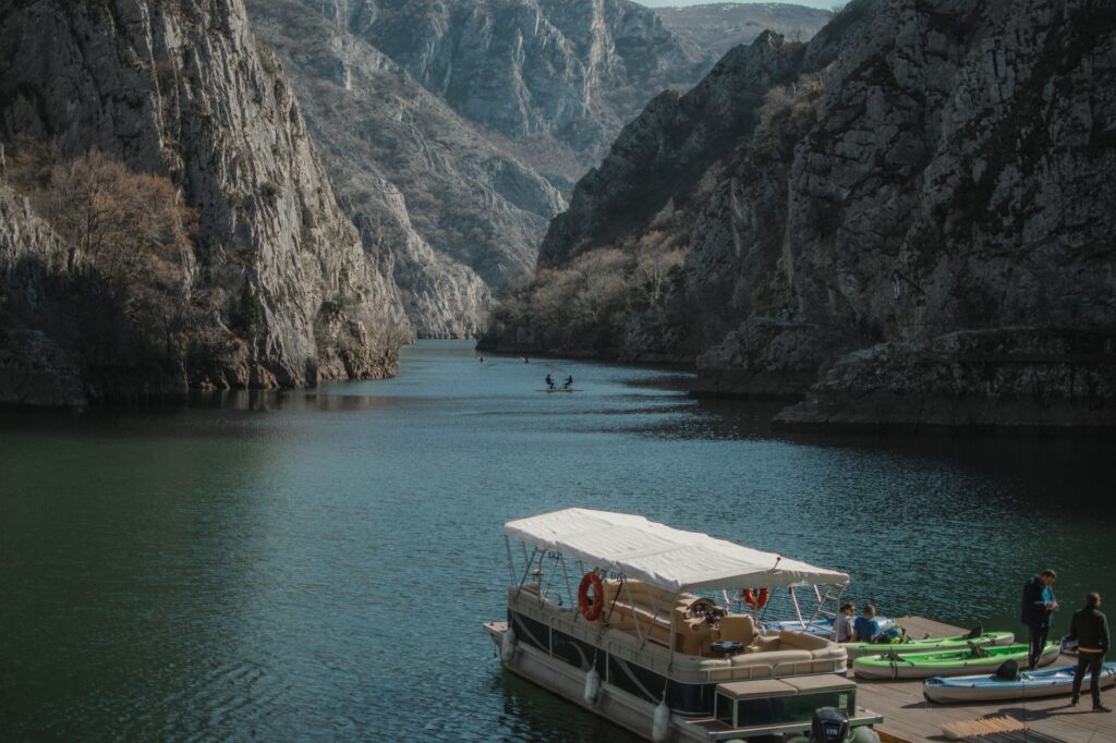 Skopje, North Macedonia — Stunning view of Matka Canyon with a boat and kayaks surrounded by towering cliffs.