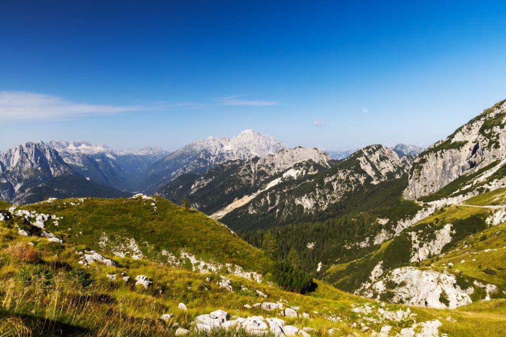 Soča Valley, Slovenia — Explore the magnificent landscapes of Julian Alps with lush green valleys and rugged peaks under a clear azure sky.